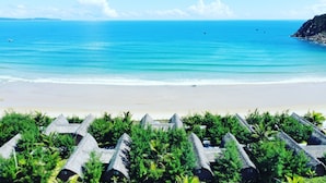 A beach resort with thatched-roof huts and a view of the ocean. - Hoa Loi Resort (Xuan Canh)