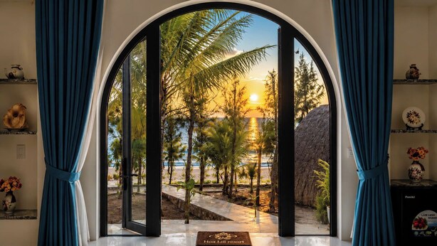 A room with a view of a beach, a thatched structure, and a sign indicating 'Hoà Dĩm' resort. - Hoa Loi Resort (Xuan Canh)