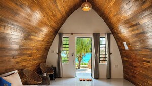 A bedroom with a large bed, a view of the beach, wooden walls, and a ceiling light. - Hoa Loi Resort (Xuan Canh)