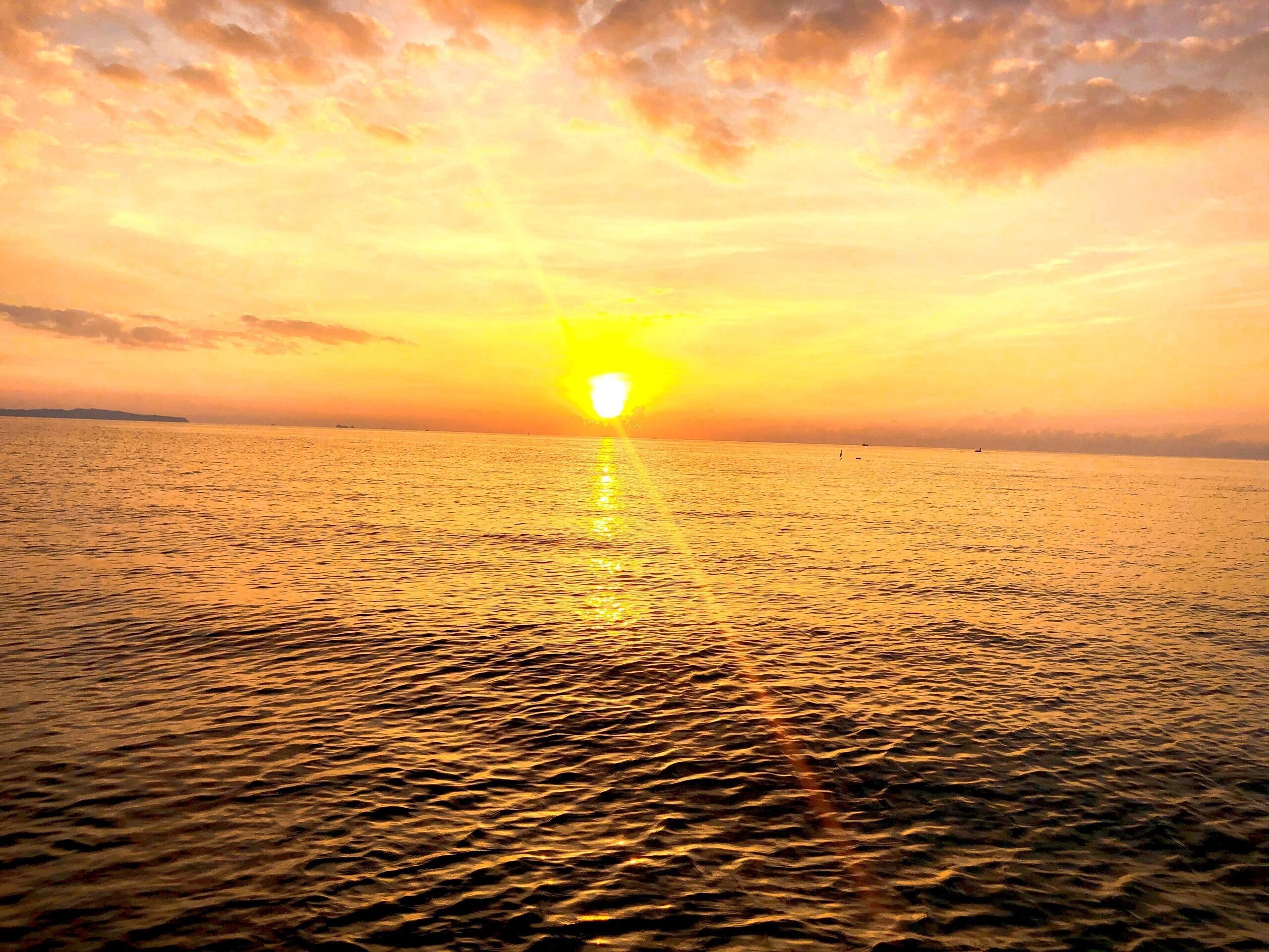 A sunset over a calm sea with a clear horizon.