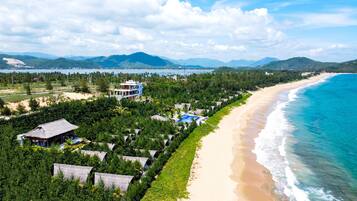 A coastal resort with a beachfront, a large building with multiple levels, and a dense forested area.