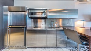 Une cuisine moderne dotée d’appareils électroménagers en acier inoxydable, d’un four encastré et d’un coin bar.