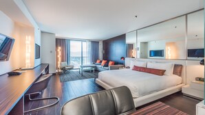 Une chambre d’hôtel moderne, dotée d’un grand lit, d’un bureau avec une chaise, d’un canapé et d’une télévision.