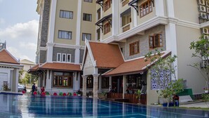 Ein Hotel mit Schwimmbad, mehreren Balkonen und traditioneller Architektur.
