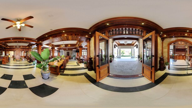 Eine geräumige Lobby mit Schachbrettmuster-Boden, Holzsäulen und einem Deckenventilator.