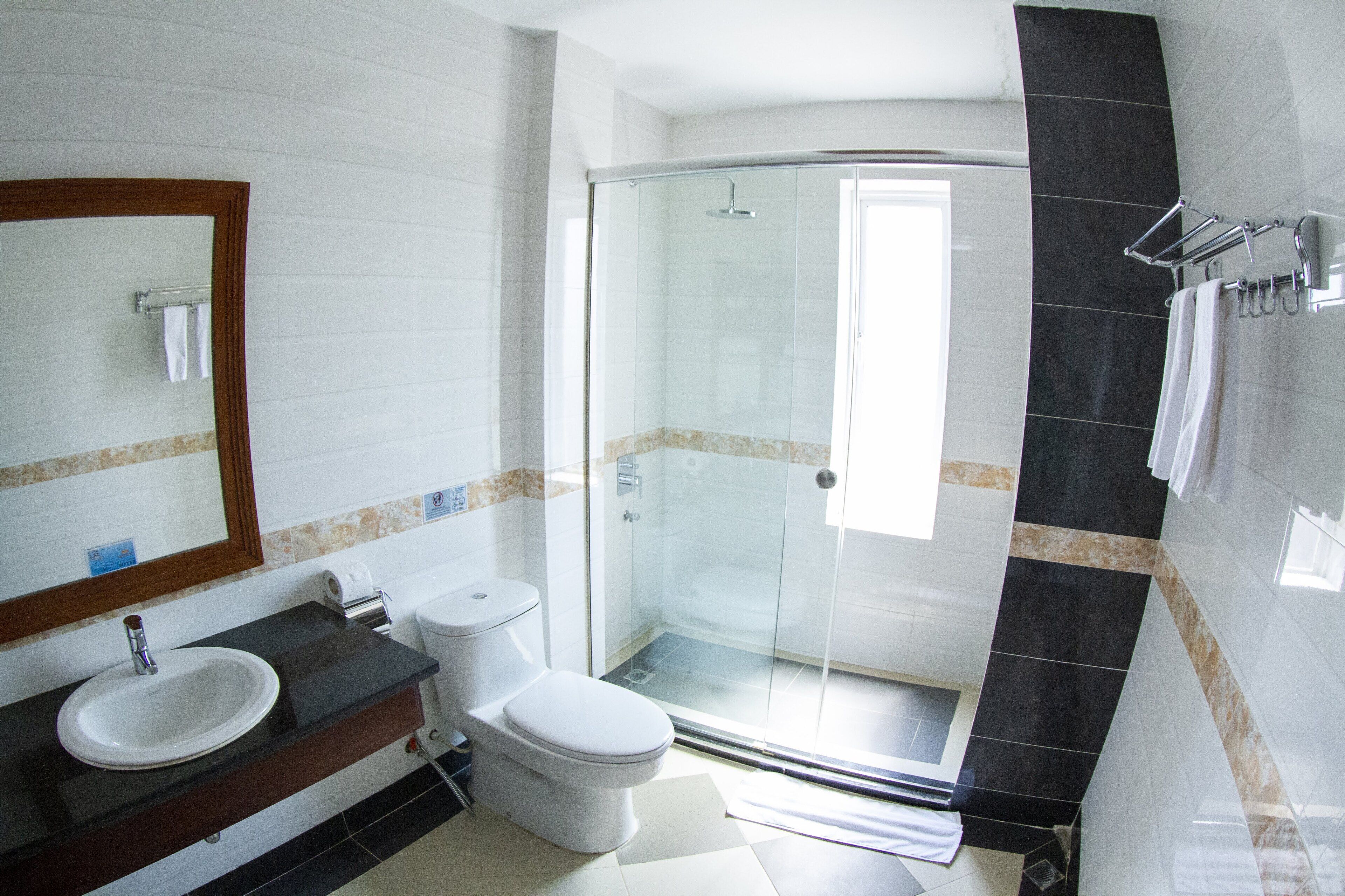 Un baño con ducha envuelta en vidrio, lavamanos e inodoro.