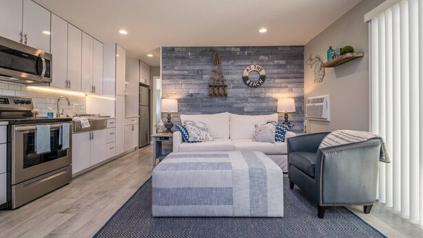 A modern kitchen with stainless steel appliances, a dining area with a sofa and lamps, and a bedroom with a bed and a nightstand. - Lakeside Serenity Villa with Private Patio (Bridgman)