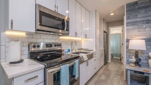 A modern kitchen with stainless steel appliances, white cabinetry, and a tiled backsplash. - Lakeside Serenity Villa with Private Patio (Bridgman)