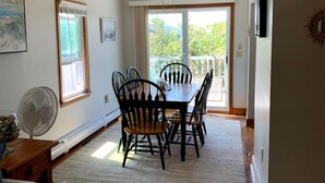A dining area with a table and chairs, a ceiling fan, and a view of the outdoors.