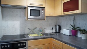 Una cocina con microondas, estufa, lavaplatos y armarios.