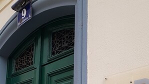 Una puerta doble verde con cerradura electrónica, un cartel sobre la puerta y un panel de comunicación en la pared.