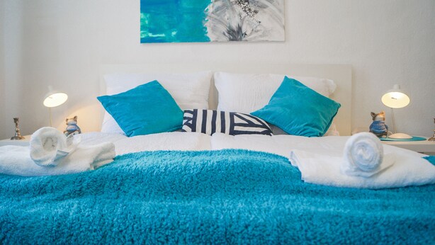 A neatly made bed with blue and white bedding, two decorative pillows, and a blue throw blanket. - Modern Apartment in The Heart of Vienna 5 (Vienna)