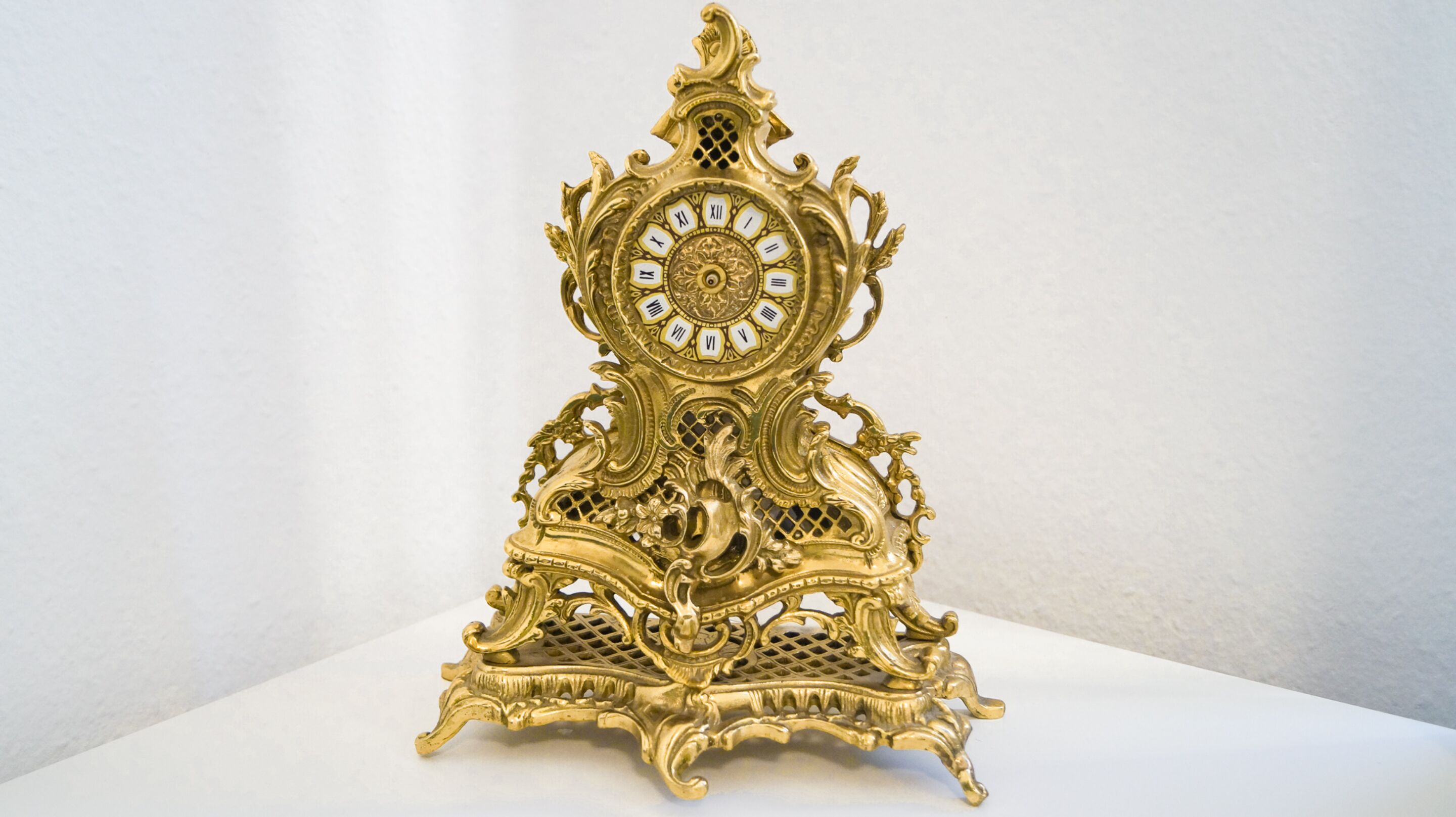 A golden ornate clock with intricate designs and a decorative base.