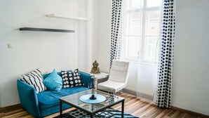 A modern living room with a blue sofa, a glass coffee table, and a white armchair. - Modern Apartment in The Heart of Vienna 5 (Vienna)