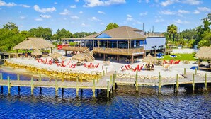 Ein Hotel am Wasser mit einer Holzterrasse, Sitzgelegenheiten im Freien und einem Gebäude mit blauem Dach.