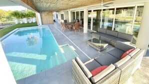 Ein Pool ohne Ende mit freiem Blick auf den Himmel, eine überdachte Terrasse mit Gartenmöbeln und ein modernes architektonisches Design mit Bambusdecke.
