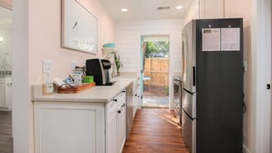 A kitchen with white cabinets, a black refrigerator, a coffee maker, and a wooden floor. - Unbeatable Location - Beaches & DT - Kid Friendly (Mount Pleasant)