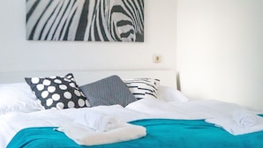 A neatly made bed with white and teal bedding, two pillows with polka dot and striped patterns, and a zebra-striped wall art piece above. - Modern Apartment in The Heart of Vienna 6 (Vienna)