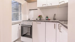 A kitchen with white cabinets, a stove, a sink, and a window. - Modern Apartment in The Heart of Vienna 6 (Vienna)