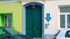 A green double door with a number 7 sign above it, a keypad on the wall to the right, and a car parked in front. - Modern Apartment in The Heart of Vienna 6 (Vienna)
