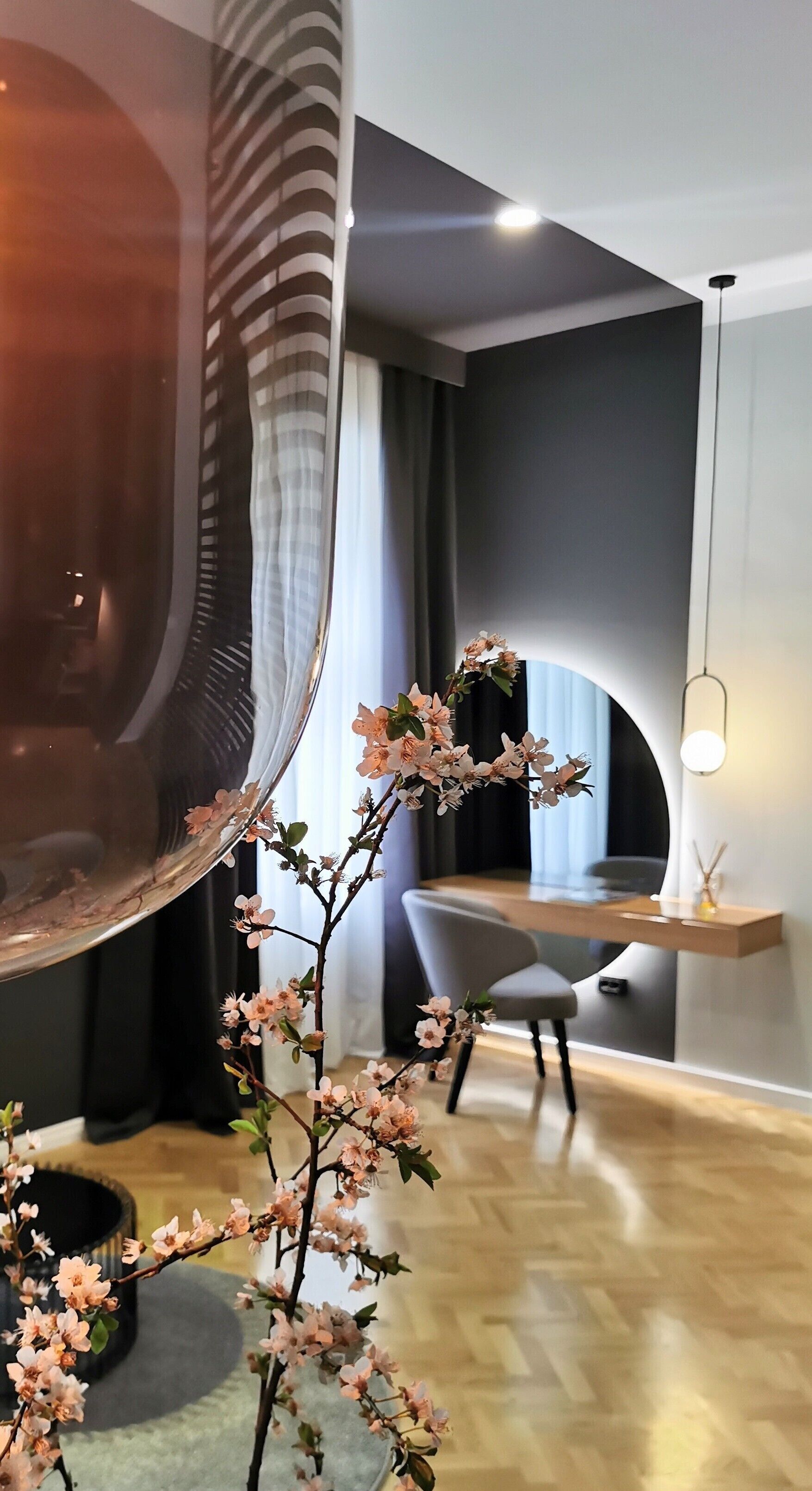A modern interior with a curved mirror, a desk, and a chair.