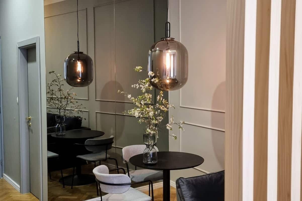 Un espace repas moderne avec une table ronde, deux chaises et un vase rempli de fleurs.