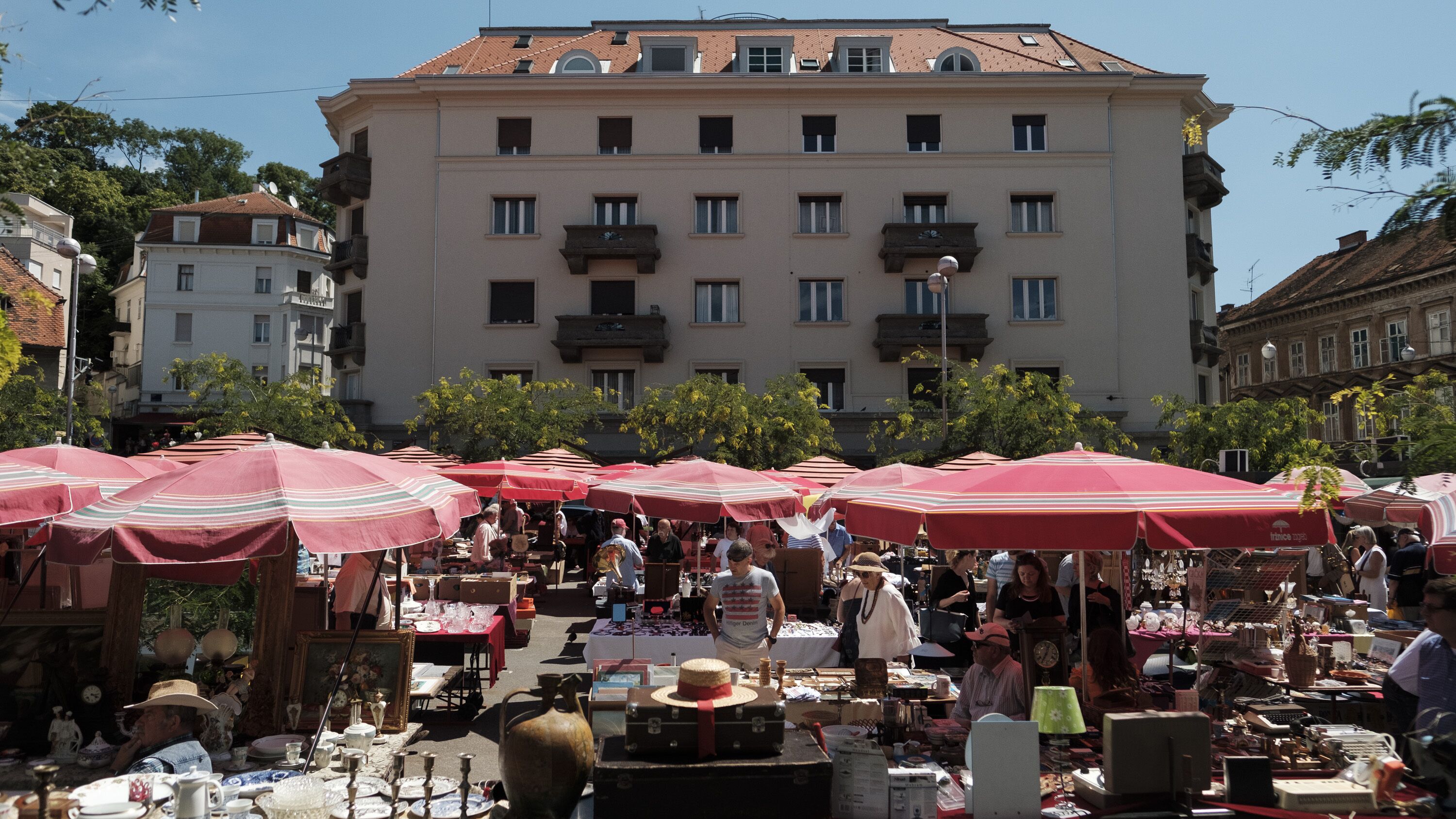 Un mercado al aire libre con mesas y sombrillas, rodeado de edificios.