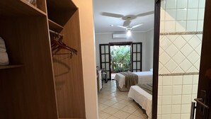 Habitación de hotel con un armario de madera, una cama con cubrecama blanco, un ventilador de techo y vistas al exterior.