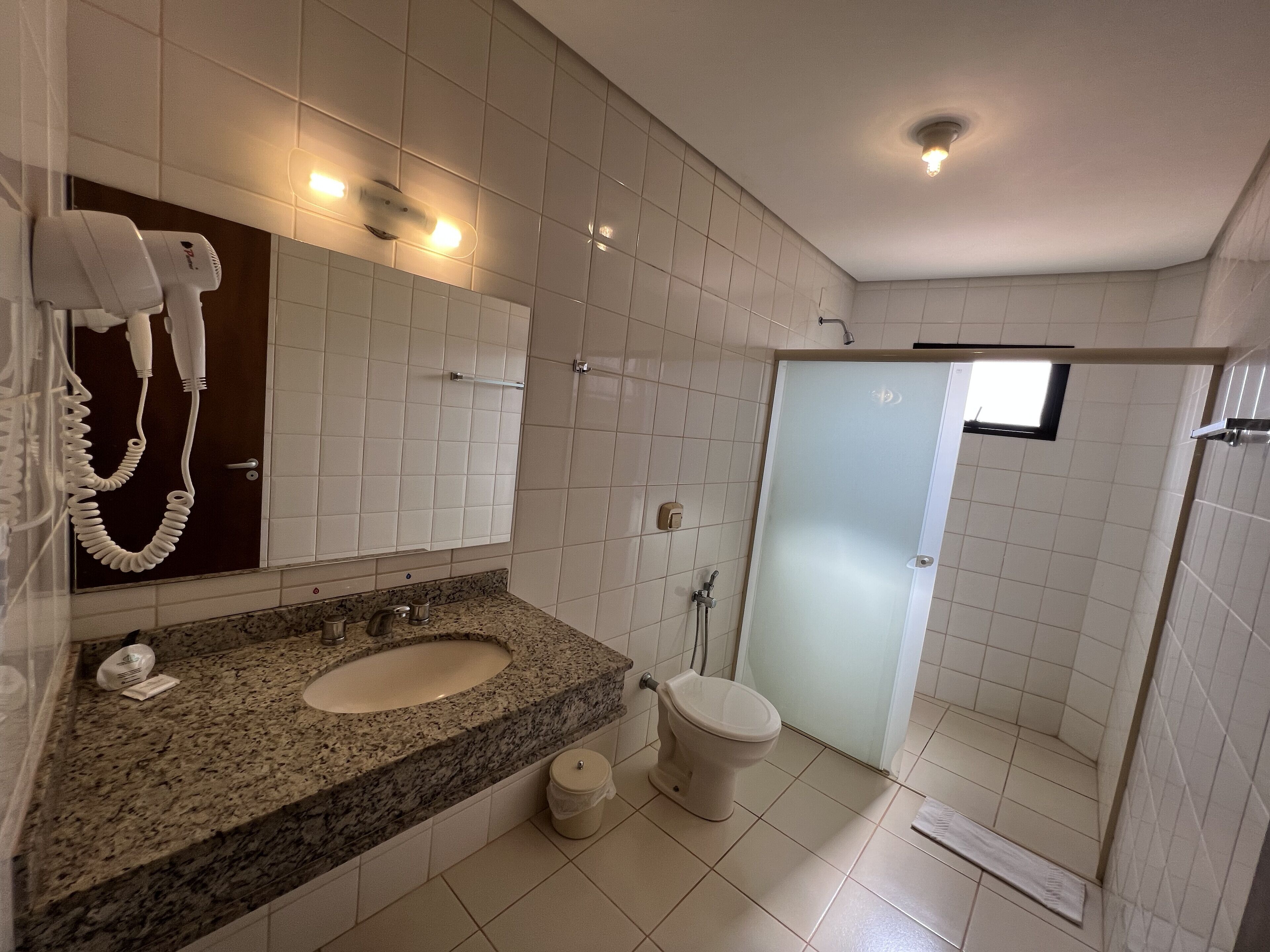 Un baño moderno con lavamanos de granito, inodoro blanco y cabina de ducha de vidrio.