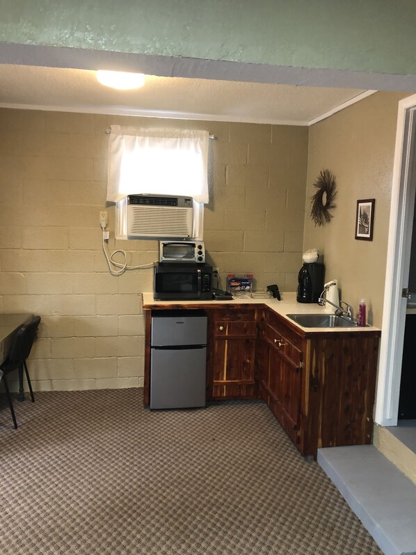 A compact kitchen with a refrigerator, microwave, and coffee maker.