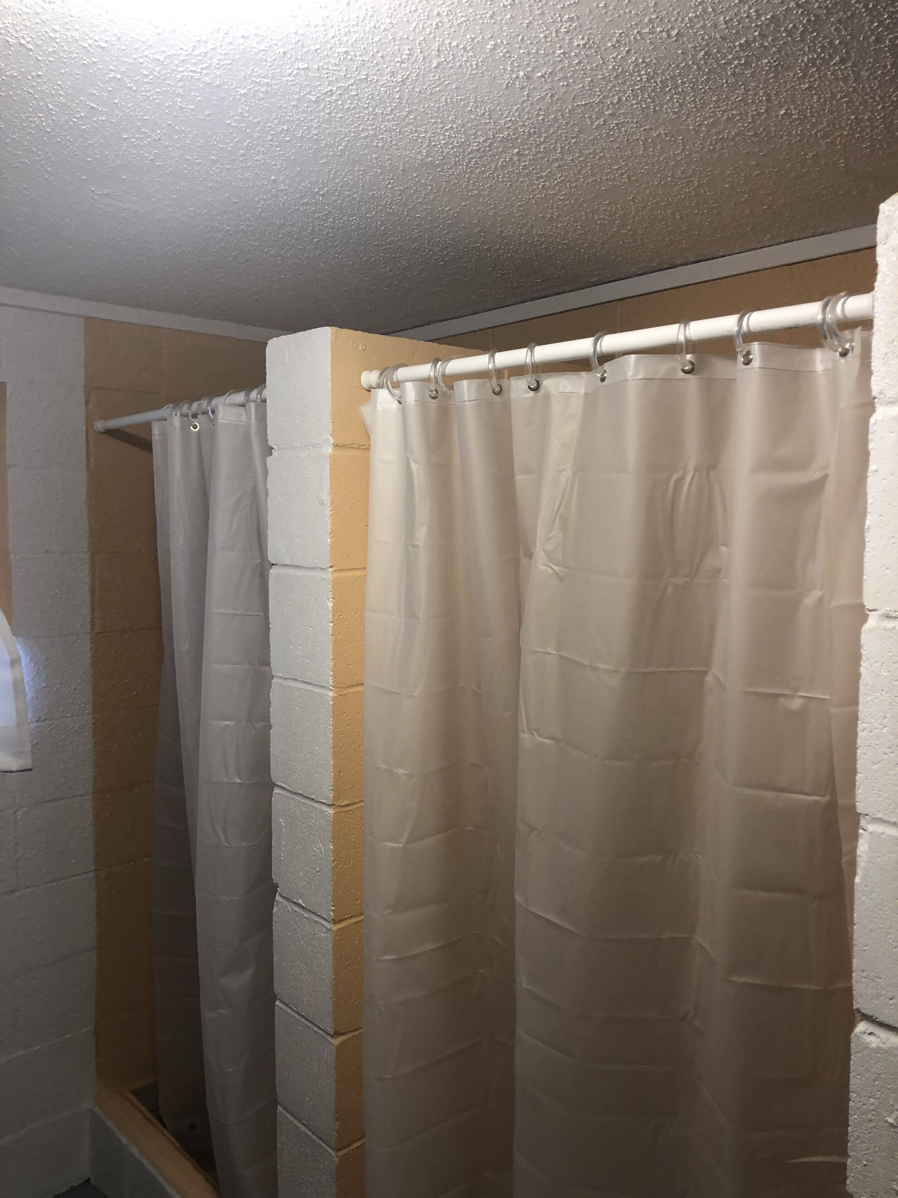 A shower area with a white curtain and a white towel hanging on the wall.