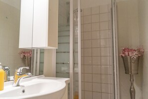 A bathroom with a white sink, a mirror, and a shower area.