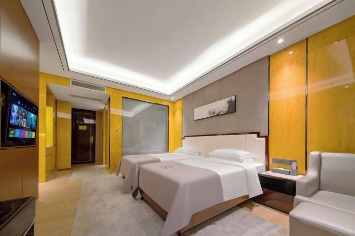 A hotel room with a bed, a TV, and a seating area.