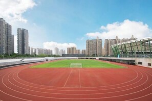 A large, empty stadium with a red track and a green field, surrounded by high-rise buildings. - Diya Hotel (Shenzhen Baoan Yifang City Branch) (Shenzhen)