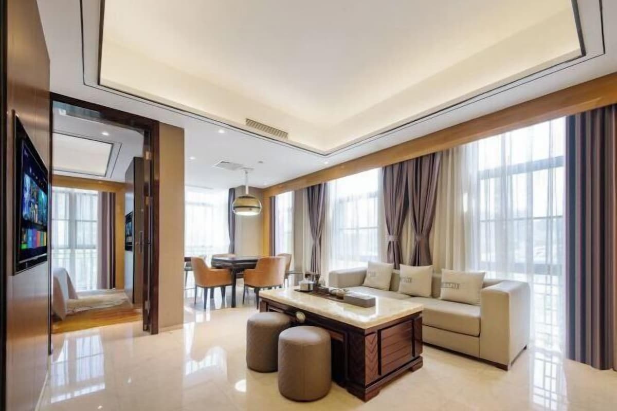 A modern living room with a sofa, ottomans, a coffee table, and a TV.