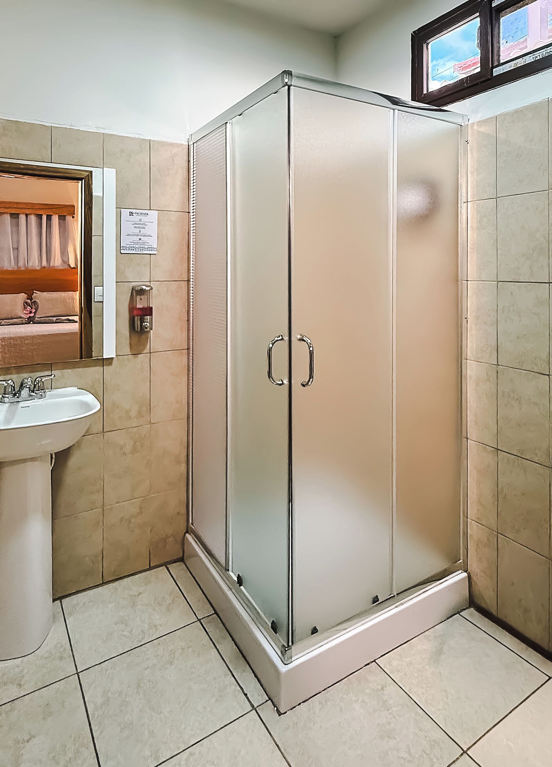Un bagno con doccia vetrata, lavandino e specchio.