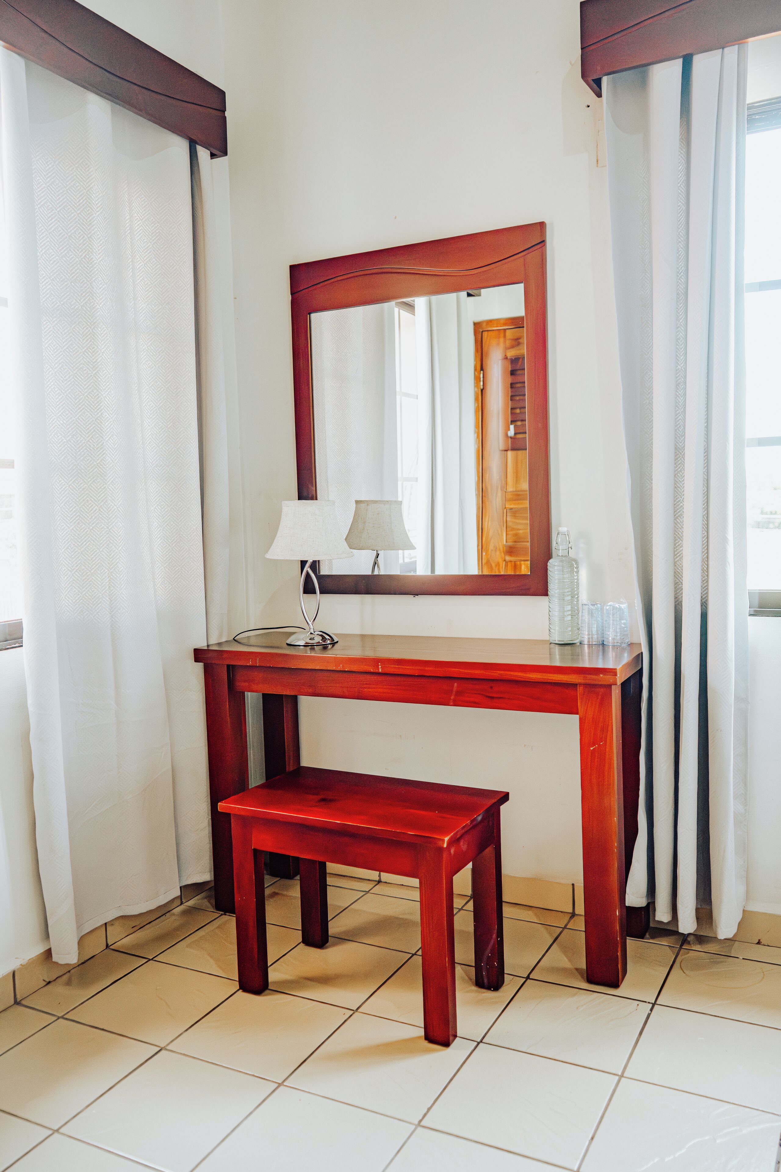 A wooden desk with a mirror, a small table, and a lamp.