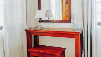 A wooden desk with a mirror, a small table, and a lamp.