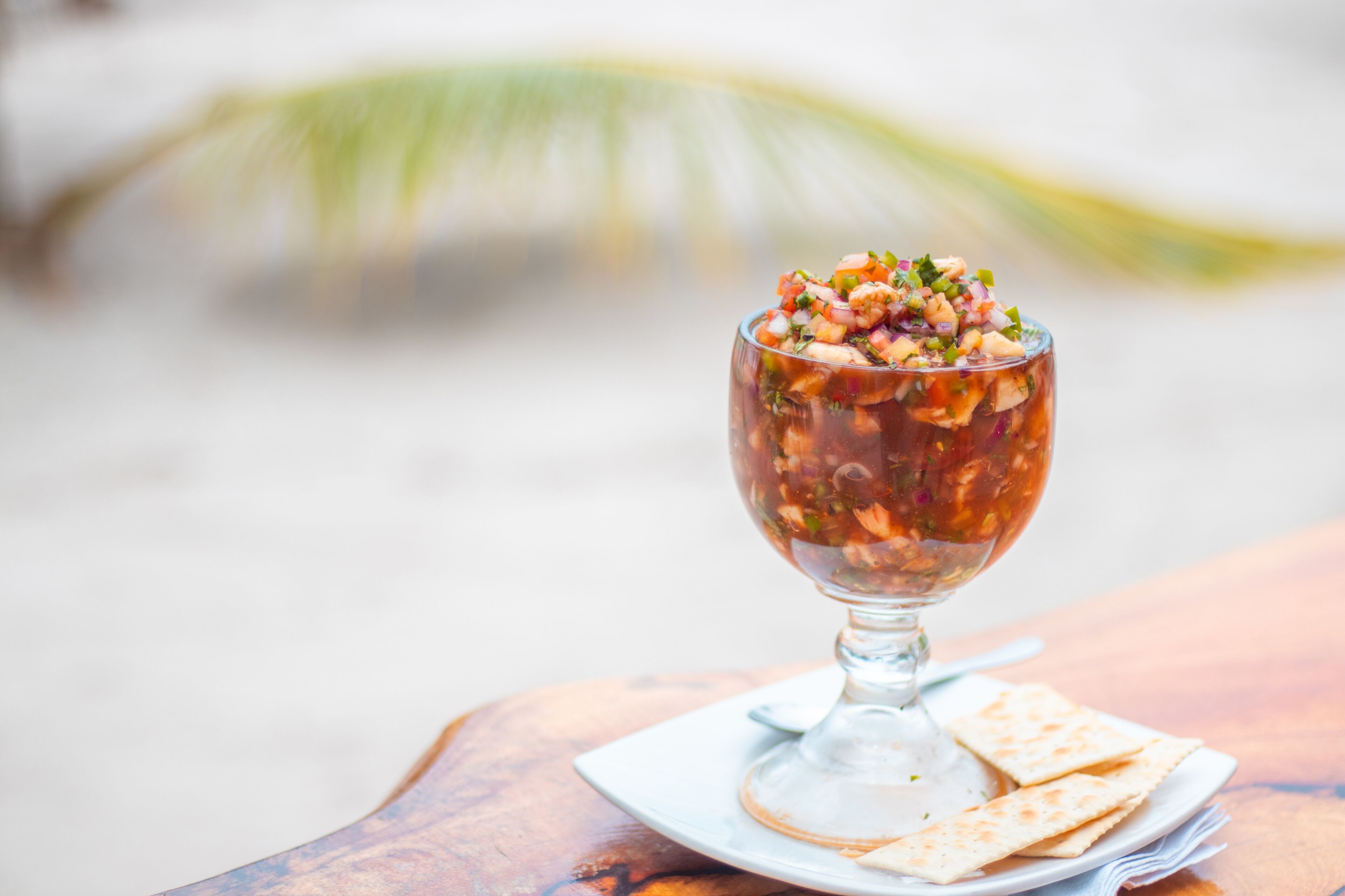 Un vaso de salsa con totopos sobre una mesa de madera.