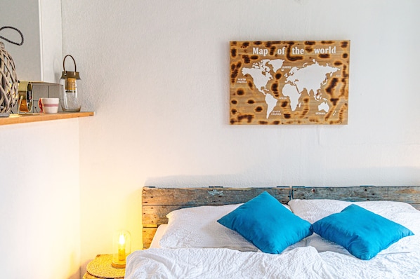 A bed with two blue pillows, a wooden headboard, and a wall-mounted world map.