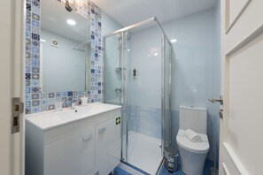 Enjoy a refreshing shower in the bathroom, featuring a glass-enclosed shower, white sink, and toilet.