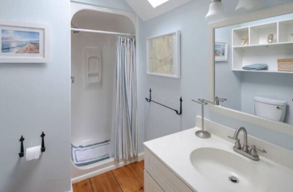 A bathroom with a shower, a sink, and a mirror. - Cape Cod Cottage steps from Private Beach (Mashpee)