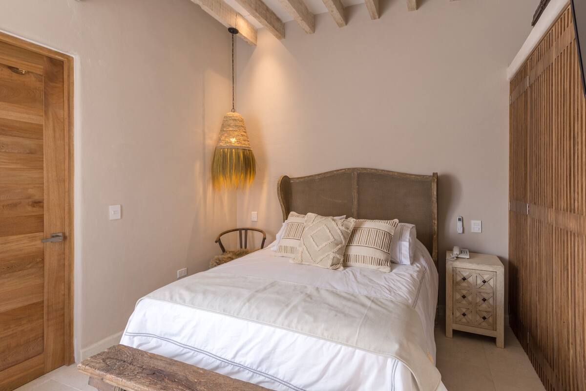 Une chambre à coucher avec une tête de lit en bois, une table de chevet et une lampe suspendue.