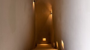 Un couloir étroit et bien éclairé, avec un escalier menant à un niveau supérieur.