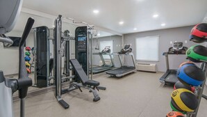 A gym with cardio equipment, weight machines, and a rack of medicine balls. - WoodSpring Suites North Ft Worth Alliance TX Speedway (Fort Worth)