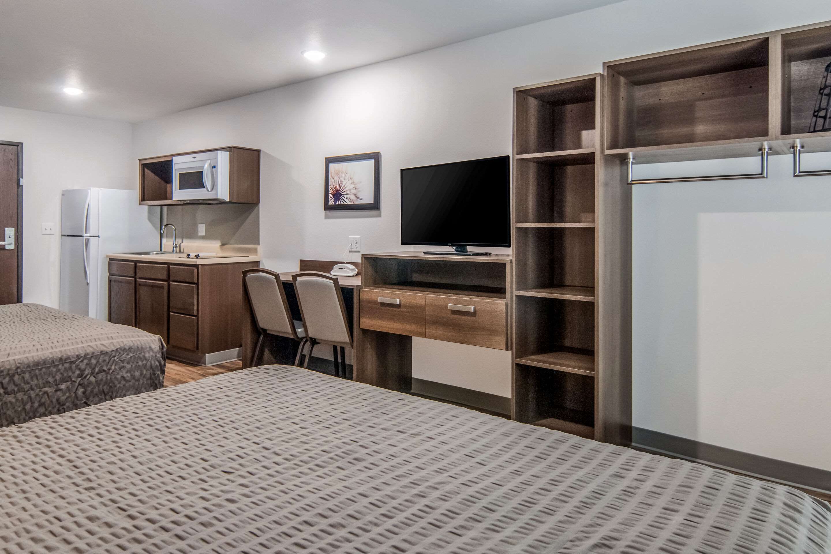 Quarto de hotel compacto com cozinha compacta, cama, escrivaninha e televisão.