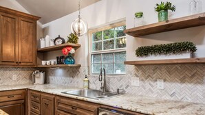 A kitchen with wooden cabinets, a herringbone tile backsplash, a double sink, and a dishwasher.