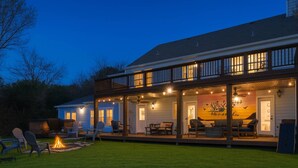 A two-story house with a covered porch, outdoor seating, and a fire pit.