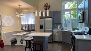 A modern kitchen with a central island, stainless steel appliances, and a view of the outdoors. - Upscale Modern Private Cottage (Kirkland)