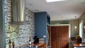 Eine moderne Küche mit einer zentralen Kochinsel, Edelstahlgeräten, einer gemusterten Spritzschutzeinrichtung und Holzschränken.